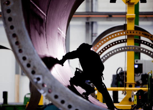 Photo of a manufacturer in shadow working on a wind turbine.